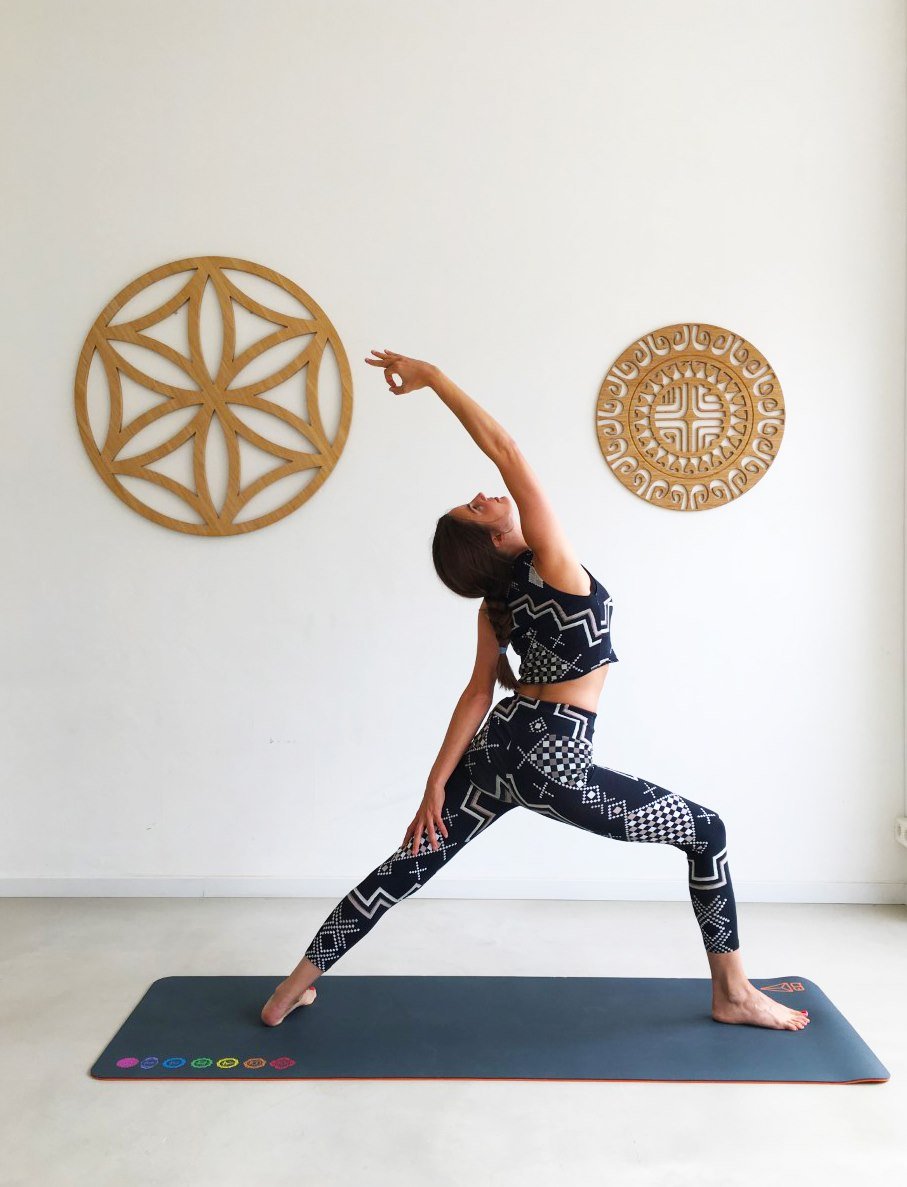 Posture du guerrier en yoga, mandalas en bois sur le mur du studio